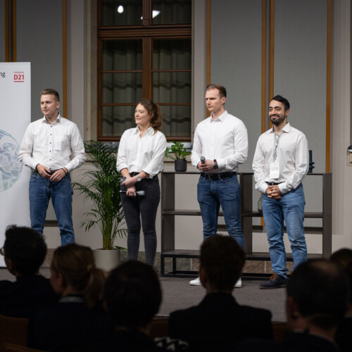 4 junge Personen zusammen mit Moderator Johannes Büchs auf der Bühne.
